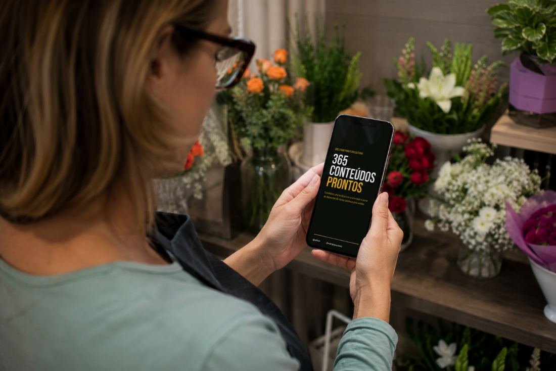 Foto: mulher olhando para o celular na floricultura